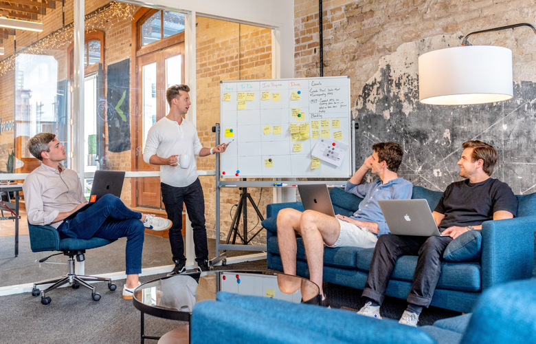 A group of four business people planning on an office whiteboard