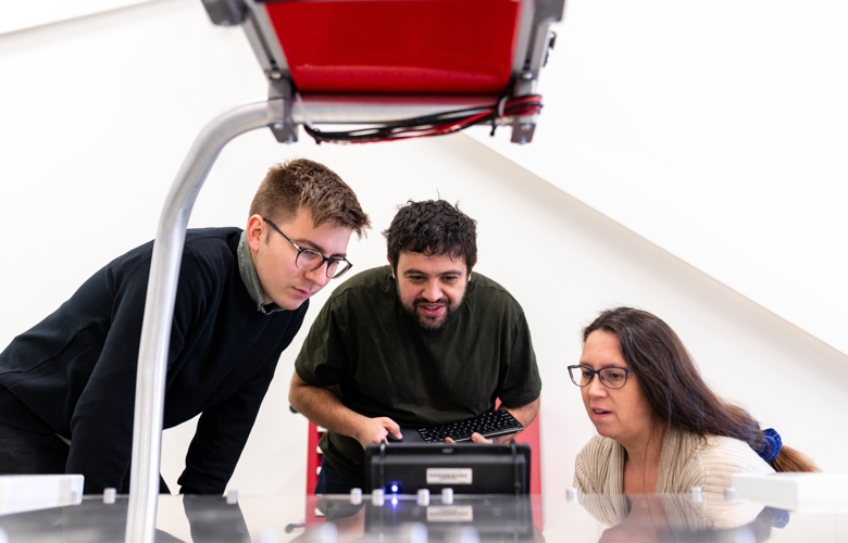 Three business people running a test using a black computer